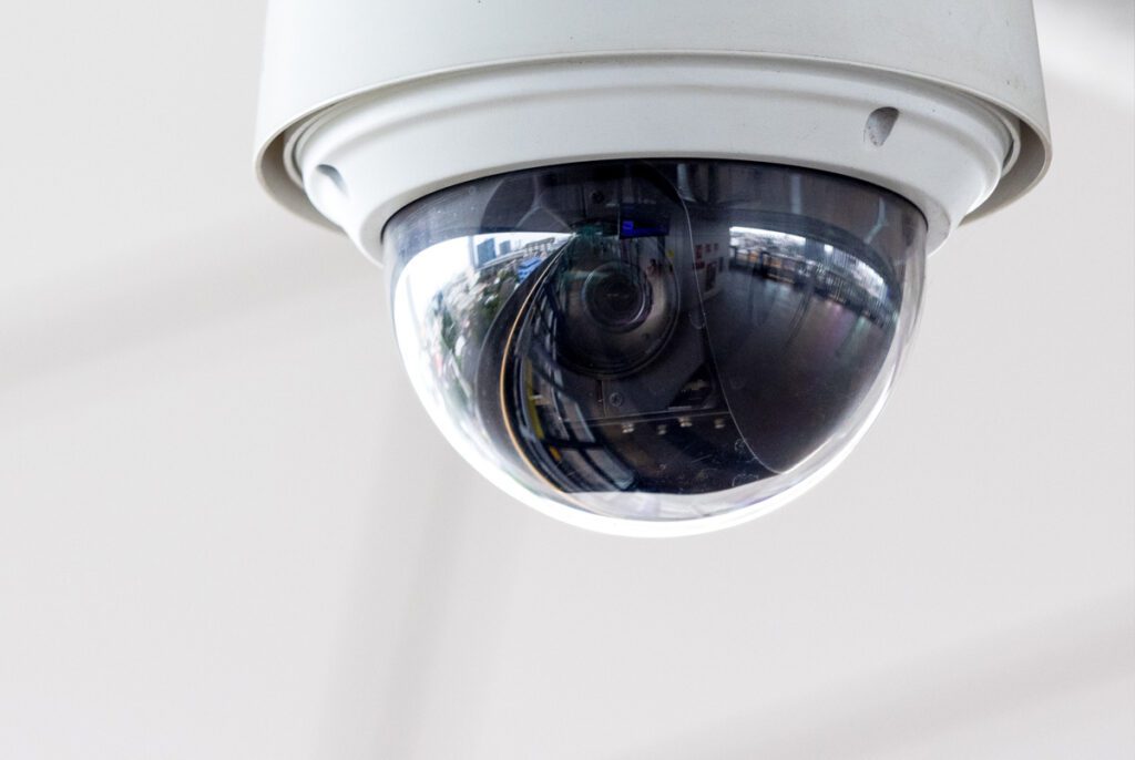 Closeup of white dome type cctv digital security camera installed on ceiling for observation.